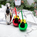 Metallic penguin shaker with red and green cups on a marble surface with Christmas decorations.