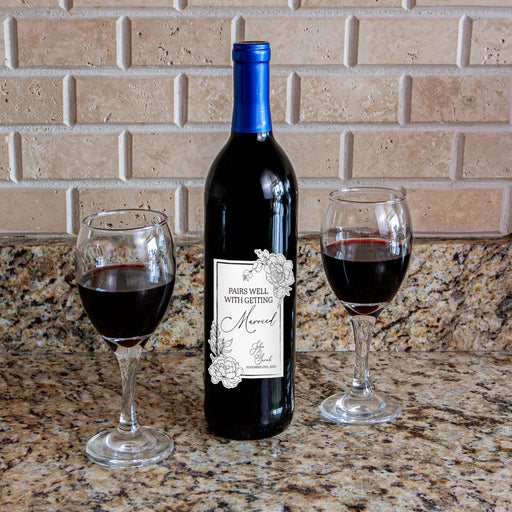 Wine bottle with a label and two glasses of red wine on a countertop.