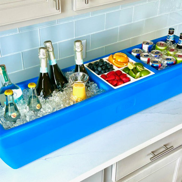 Blue drink cooler with bottles, fruits, and snacks on a kitchen counter.