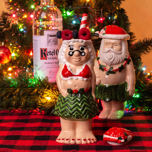 Two ceramic figures of a ms. claus and santa in hula outfits 