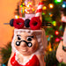Decorative figure of ms. claus with a Santa hat, berries, and a candy cane against a festive background.