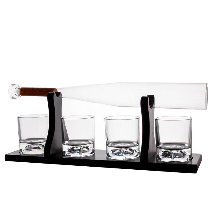 A whiskey decanter set with a clear glass bottle resting horizontally on a black metal stand, with four matching clear glass tumblers on the base, photographed on a white background.
