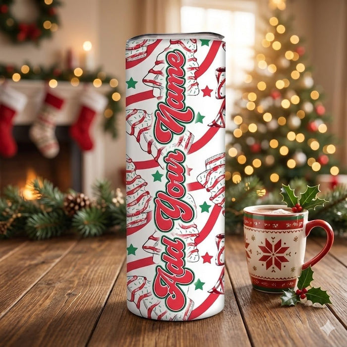 Tumbler with 'Add Your Name' text in a festive design on a wooden surface with a Christmas tree in the background.