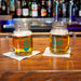 Two mason jars with beer on a bar counter, featuring 'Collins's' branding.