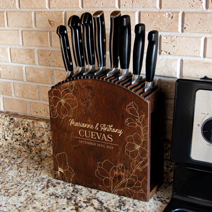 Wooden knife block with engraved names and dates on a kitchen counter.
