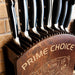 Set of knives in a wooden block with 'Prime Choice' branding against a brick wall.
