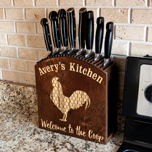 Wooden knife block with engraved rooster design and 'Avery's Kitchen' text on a kitchen counter.