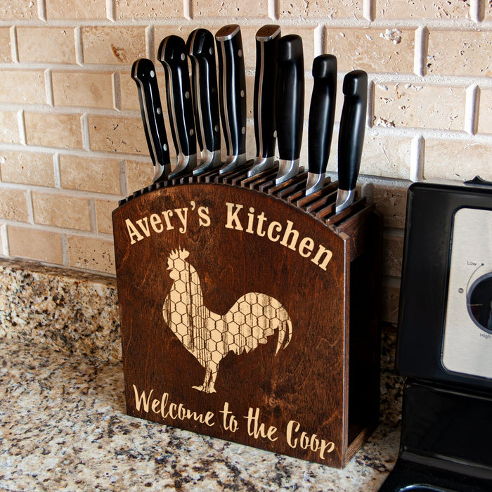Wooden knife block with engraved rooster design and 'Avery's Kitchen' text on a kitchen counter.