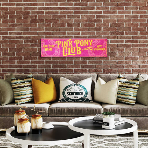 Living room with a couch, coffee table, and decorative items against a brick wall with 'Pink Pony Club' sign.