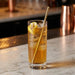 Glass of iced tea with lemon slices and a gold straw on a marble surface.