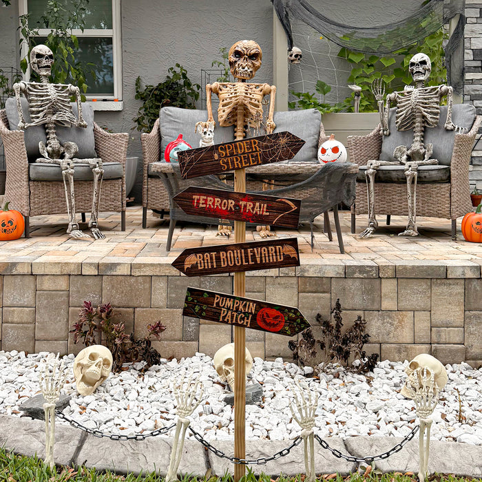 Halloween outdoor scene with skeletons, pumpkins, and a signpost on a patio.