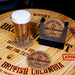 Glass of beer on a wooden surface with 'Holiday Brew Hot Chocolate' coasters.