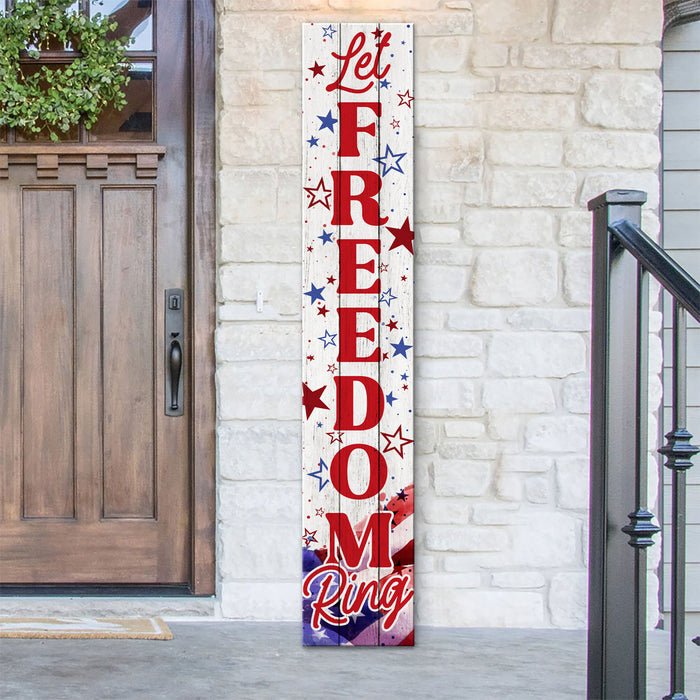 Decorative sign with 'Let Freedom Ring' text on a white background, leaning against a stone wall.