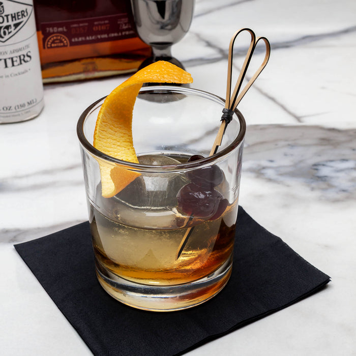 Glass of whiskey with an orange twist on a marble surface