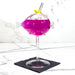 Purple cocktail in a fish-shaped glass with a straw on a marble surface