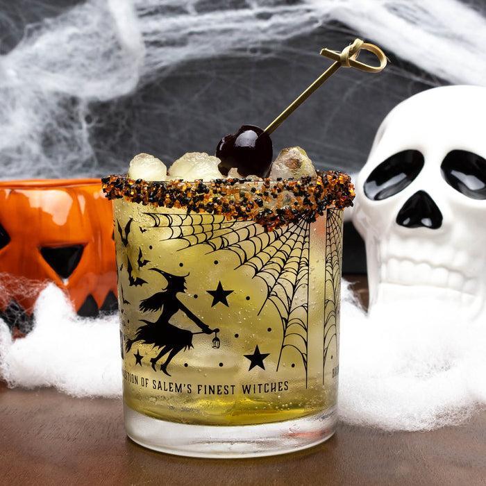 Halloween-themed cocktail with spider web design and skull decoration.