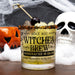 Cocktail in a glass labeled 'Witches Brew' with Halloween decorations in the background.